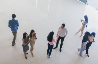 Asyalı ofis çalışanları ofis lobisinde durup konuşuyorlar..
