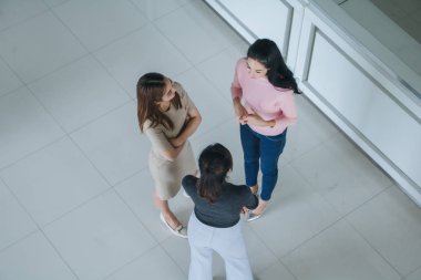 Asyalı ofis çalışanları ofis lobisinde durup konuşuyorlar..