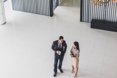 Yöneticiler ve sekreterler kapalı koridorlarda yürüyorlar.