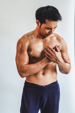 Asian man with muscular Injury to the chest from exercise on Whi