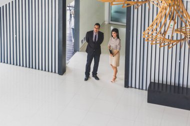 Yöneticiler ve sekreterler kapalı koridorlarda yürüyorlar.