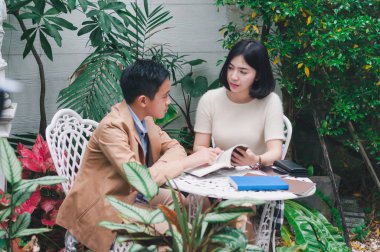 Kız kardeşi evin bahçesinde erkek kardeşine öğretiyor.