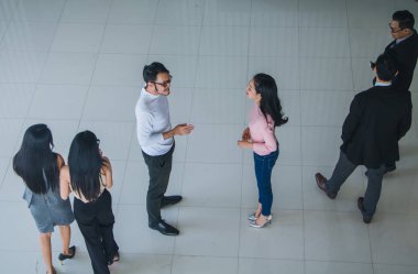 Asyalı ofis çalışanları ofis lobisinde durup konuşuyorlar..