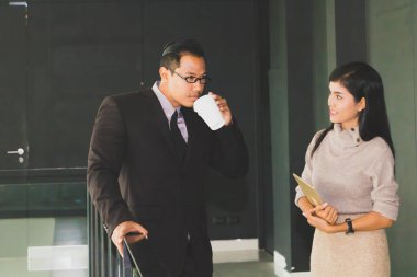 Yöneticiler ve sekreterler kapalı koridorlarda yürüyorlar.