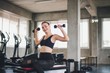 Güzel beyaz kız, halteri kaldırarak egzersiz yapıyor. 