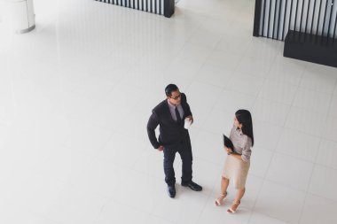 Yöneticiler ve sekreterler kapalı koridorlarda yürüyorlar.