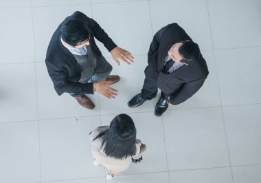 Asyalı ofis çalışanları ofis lobisinde durup konuşuyorlar..