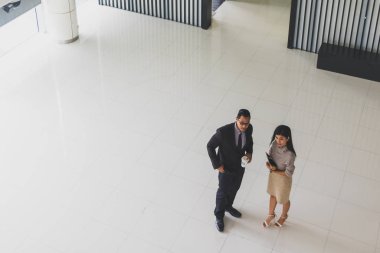 Yöneticiler ve sekreterler kapalı koridorlarda yürüyorlar.