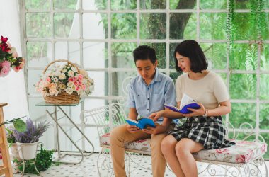 Kız ve erkek kardeş bir saksıda kitap okuyorlar.