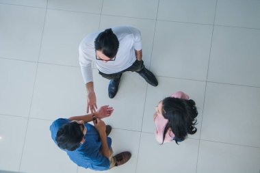 Asyalı ofis çalışanları ofis lobisinde durup konuşuyorlar..