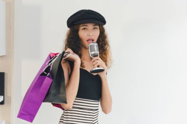 Asyalı kız alışverişi şarkı söylemek için mikrofon kullanıyor. Alışveriş konumu