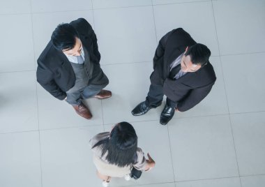 Asyalı ofis çalışanları ofis lobisinde durup konuşuyorlar..