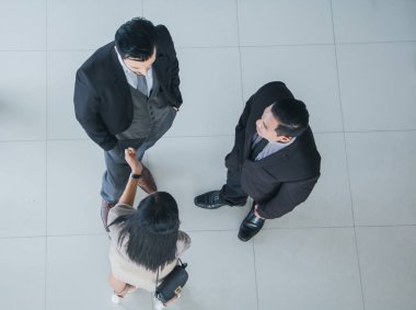 Asyalı ofis çalışanları ofis lobisinde durup konuşuyorlar..