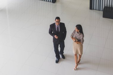 Yöneticiler ve sekreterler kapalı koridorlarda yürüyorlar.