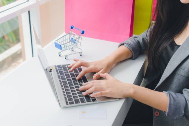 Asyalı kız internette alışveriş yapıyor. Telefon ve kredi kartıyla. Ne?