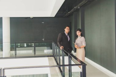 Yöneticiler ve sekreterler kapalı koridorlarda yürüyorlar.