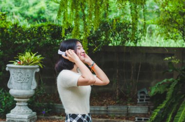 Güzel Asyalı kız bahçede müzik dinliyor..