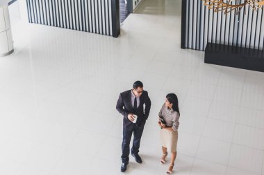 Yöneticiler ve sekreterler kapalı koridorlarda yürüyorlar.