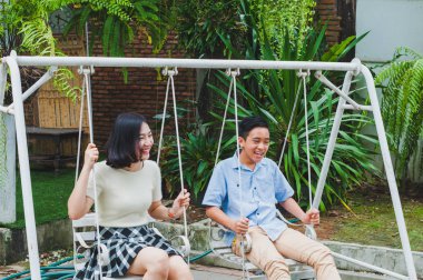 Kız ve erkek kardeş evin bahçesinde salıncak oynuyorlar.