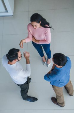 Asyalı ofis çalışanları ofis lobisinde durup konuşuyorlar..