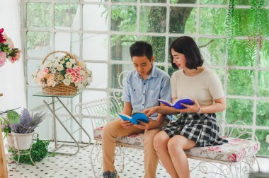 Kız ve erkek kardeş bir saksıda kitap okuyorlar.