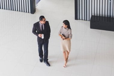 Yöneticiler ve sekreterler kapalı koridorlarda yürüyorlar.