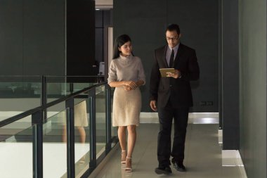 Yöneticiler ve sekreterler kapalı koridorlarda yürüyorlar.