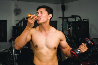 Asyalı adamın kasları var pizza yiyor ve dambılları kaldırıyor.