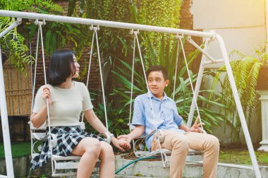 Kız ve erkek kardeş evin bahçesinde salıncak oynuyorlar.