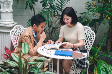 Kız kardeşi evin bahçesinde erkek kardeşine öğretiyor.