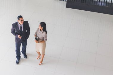 Yöneticiler ve sekreterler kapalı koridorlarda yürüyorlar.