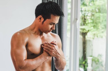 Asian man with muscular Injury to the chest from exercise on Whi