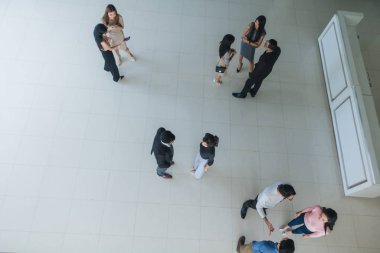 Asyalı ofis çalışanları ofis lobisinde durup konuşuyorlar..