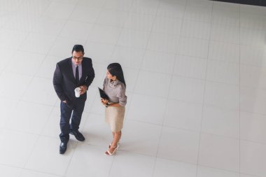 Yöneticiler ve sekreterler kapalı koridorlarda yürüyorlar.