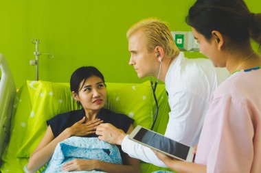 Doktor ve hemşire sethoscop kullanarak kalbi dinliyorlar.