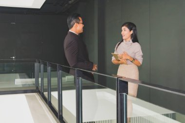 Yöneticiler ve sekreterler kapalı koridorlarda yürüyorlar.