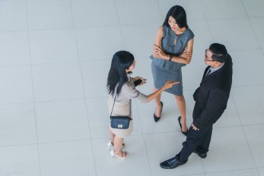 Asyalı ofis çalışanları ofis lobisinde durup konuşuyorlar..