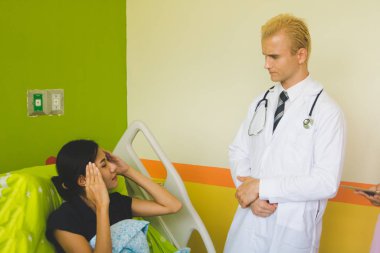 Doktor ve hemşire sethoscop kullanarak kalbi dinliyorlar.