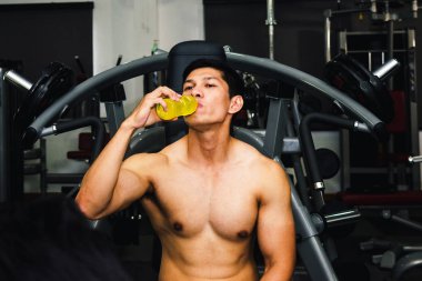 Asyalı adamın spor salonunda kas egzersizi var ve çok yorgun.