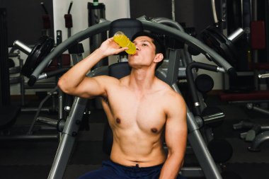 Asyalı adamın spor salonunda kas egzersizi var ve çok yorgun.