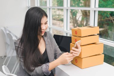 İnternetten alışveriş yapan Asyalı bir kızın portresi. Telefonla ve parayla.