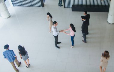 Asyalı ofis çalışanları ofiste el sıkışarak birbirlerini selamlıyorlar.