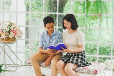 Kız ve erkek kardeş bir saksıda kitap okuyorlar.