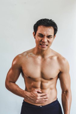 Asian man with muscular Injury to the stomach from exercise on W