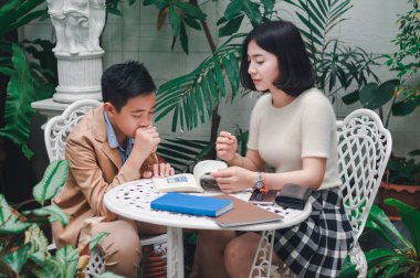 Kız kardeşi evin bahçesinde erkek kardeşine öğretiyor.