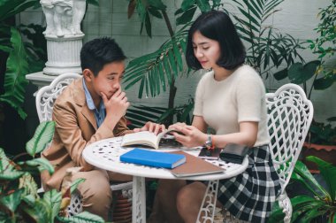 Kız kardeşi evin bahçesinde erkek kardeşine öğretiyor.