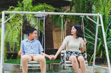 Kız ve erkek kardeş evin bahçesinde salıncak oynuyorlar.