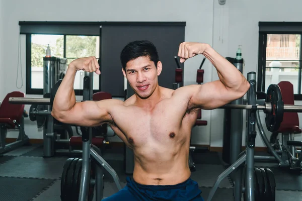 Ásia muscular homens estão levantando pesos no o ginásio . — Fotografia de Stock