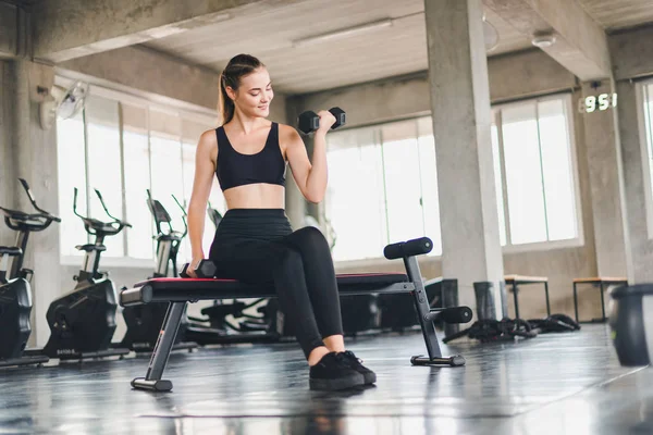 Güzel beyaz kız, halteri kaldırarak egzersiz yapıyor. 