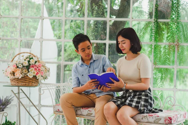 Kız ve erkek kardeş bir saksıda kitap okuyorlar.